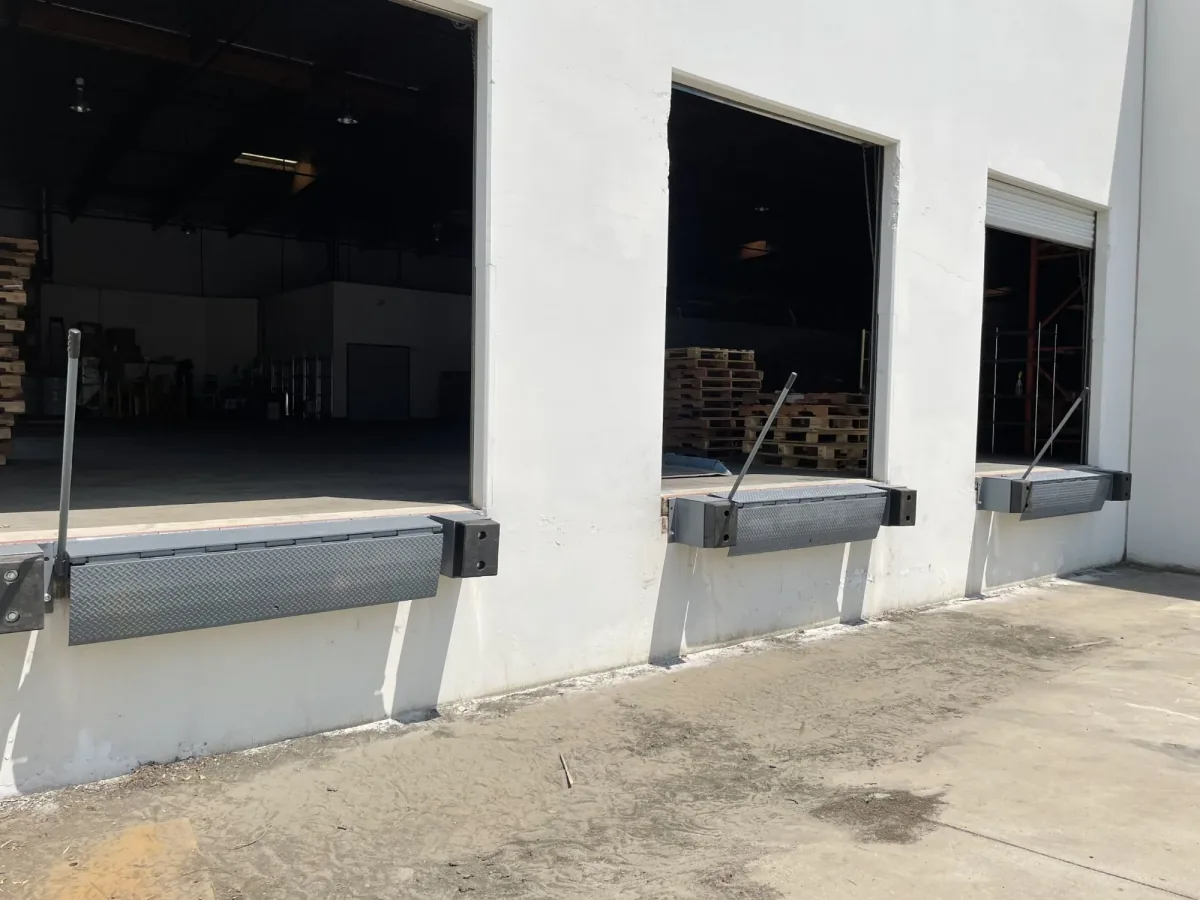 Commercial warehouse loading dock with three mechanical dock levelers and open bay doors